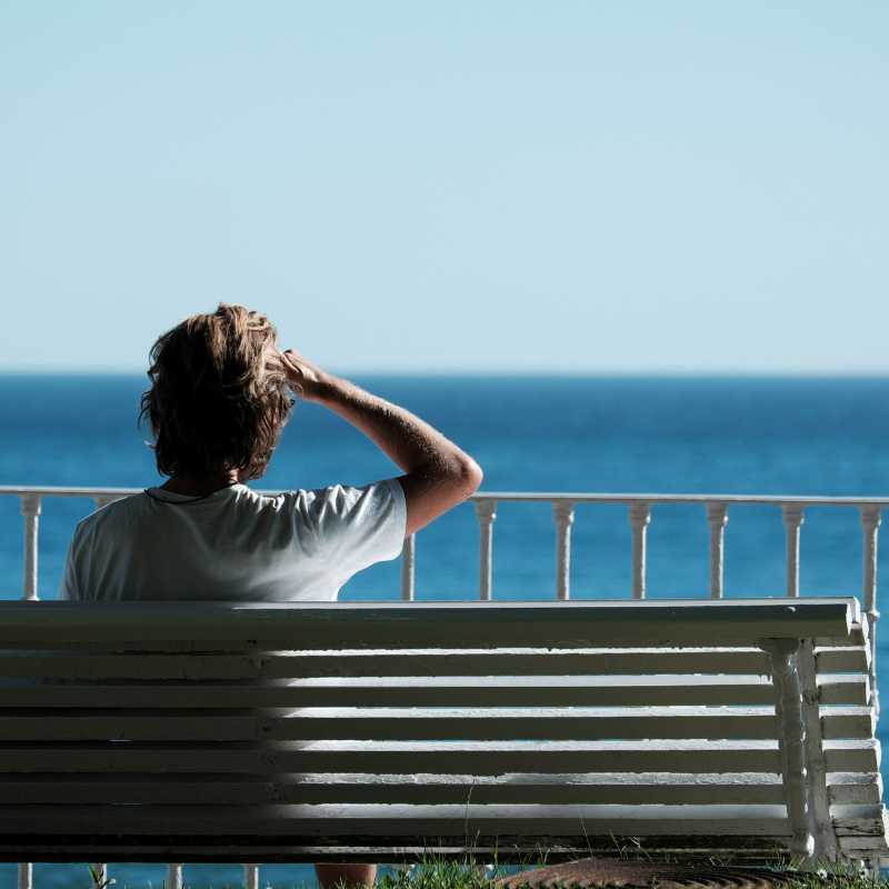 Hombre sentado en banco de espaldas mirando el mar, tiene el futuro en sus manos, un cambio de 360º de mi programa reconstruye tu vida después de una separación.
