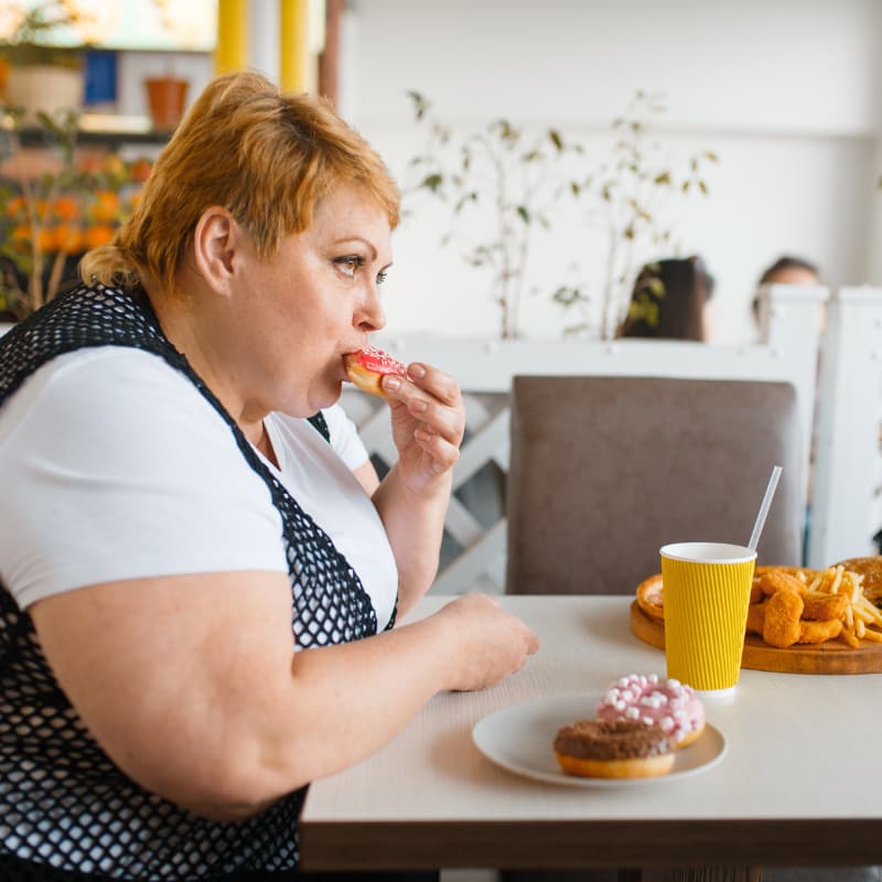 Mujer obesa que come comida basura