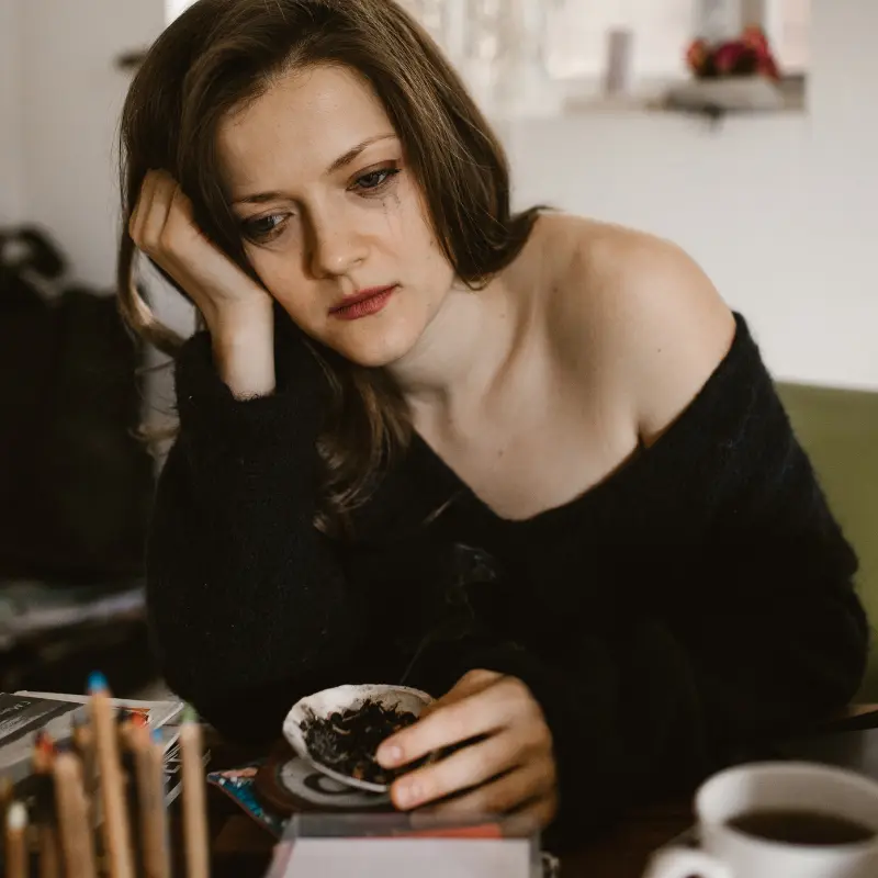 Mujer bastante joven melancólica con la cabeza apoyada y mirada perdida