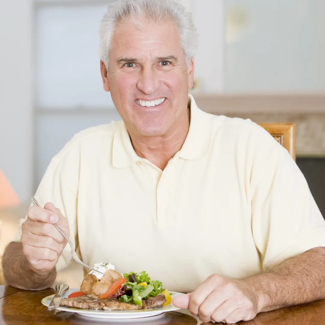 Hombre que sonríe comiendo ensalada con pescado